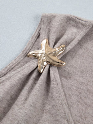 Grey V-neck knit vest with a gold starfish embellishment and draped detail.
