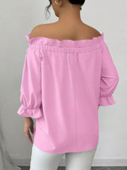 Pink off-the-shoulder blouse with ruffled neckline and cuffs.