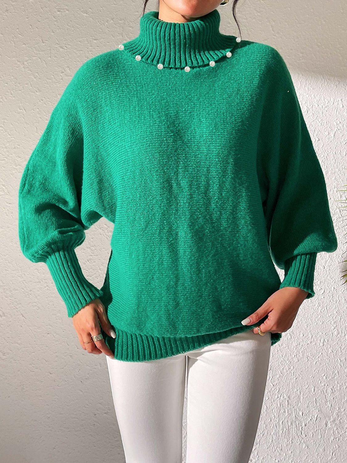 Green knit sweater with pearl-embellished turtleneck and dolman sleeves.