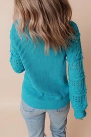 Turquoise knit sweater with textured cutout sleeves and ribbed details.