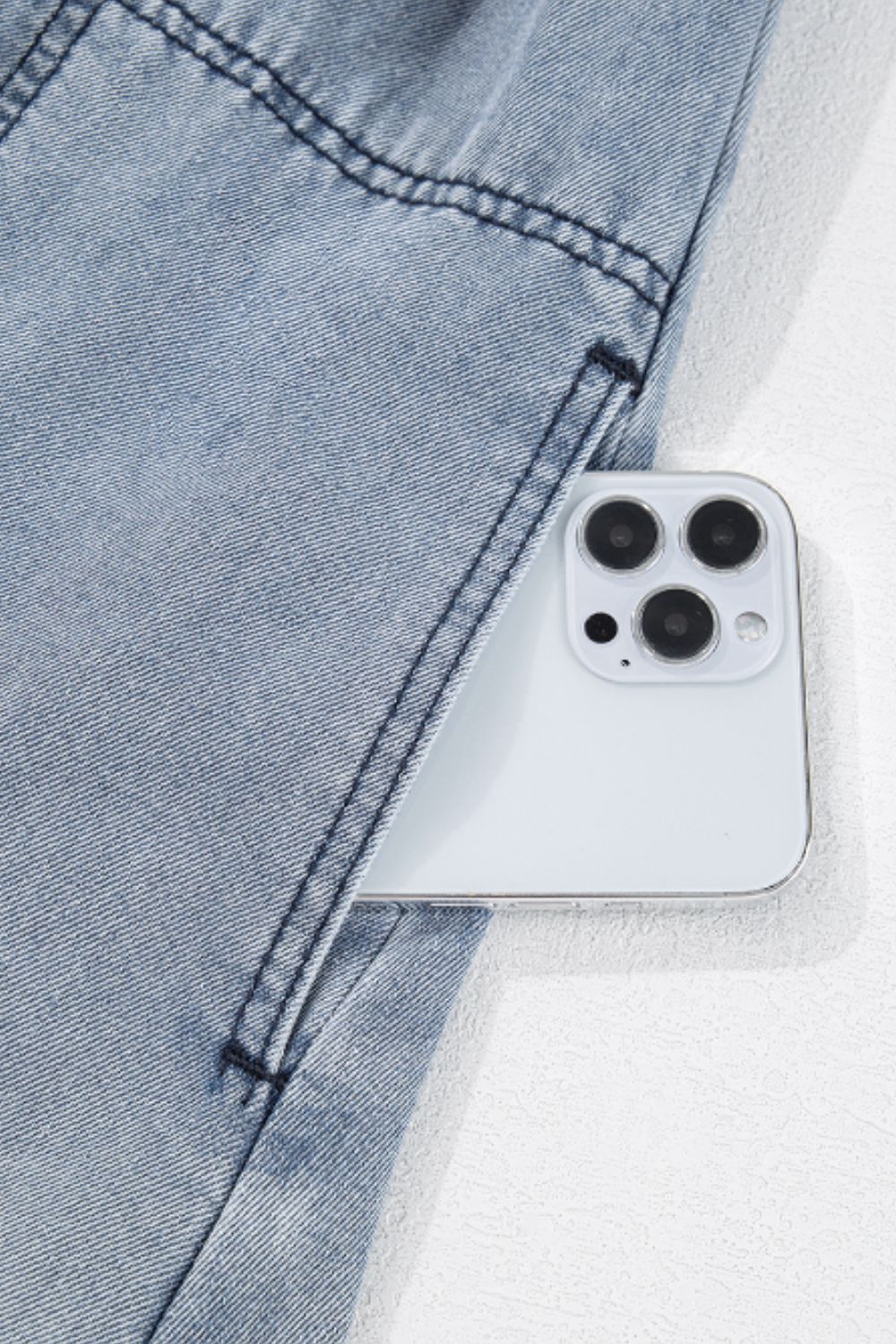 Gathered waist denim mini dress in medium wash with a phone in the pocket.