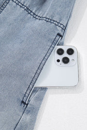 Gathered waist denim mini dress in medium wash with a phone in the pocket.
