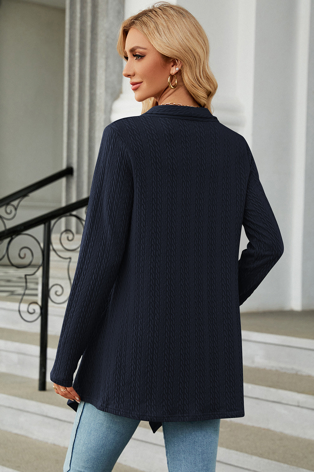 Dark blue textured knit cardigan with asymmetrical hem and long sleeves.