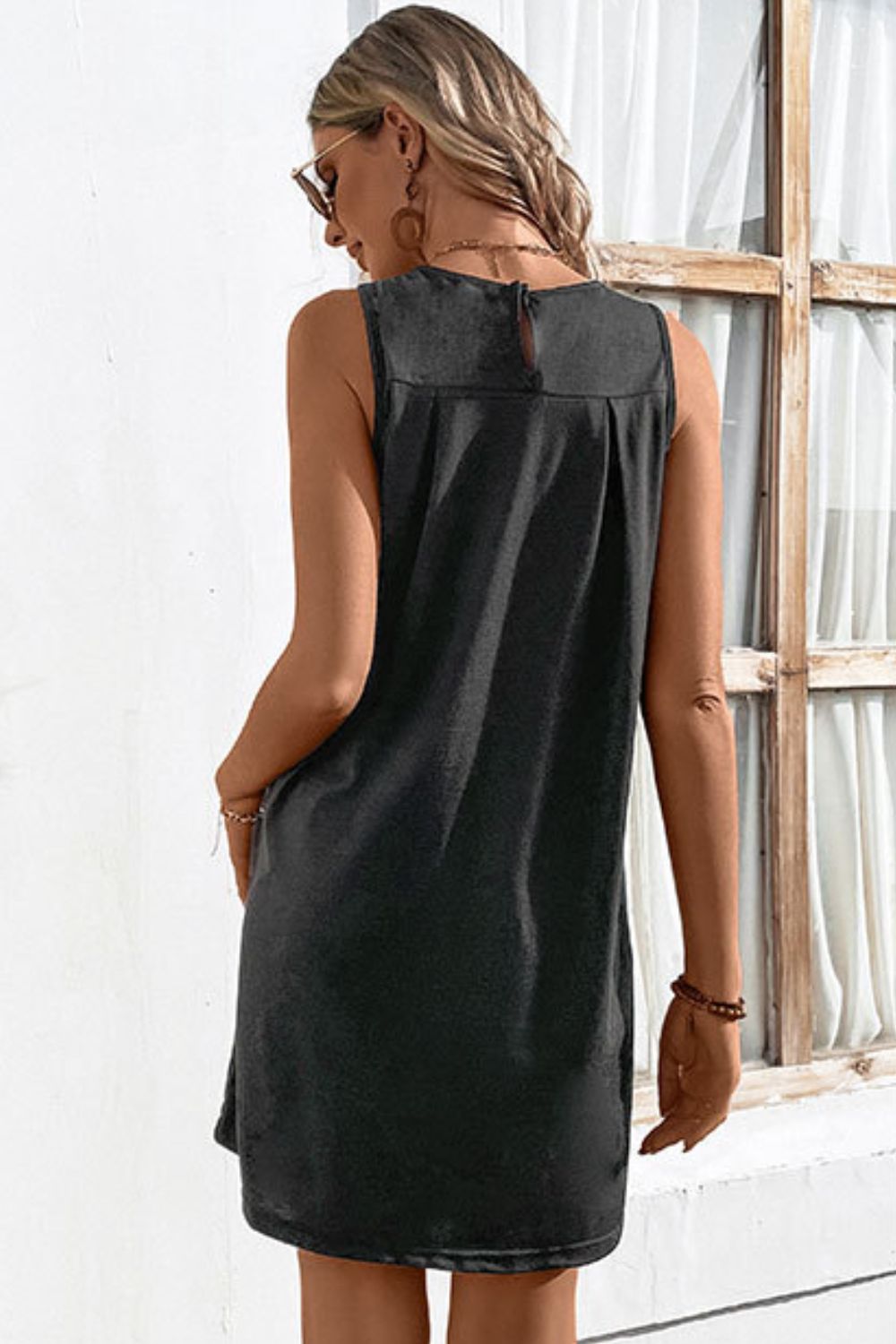 Sleeveless trapeze dress in dark gray with pleated yoke detail and back keyhole closure.