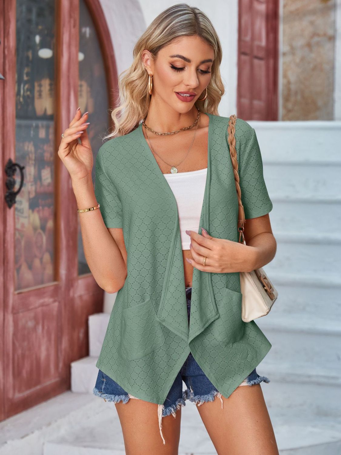 Sage green perforated shawl collar jacket with short sleeves and pockets.