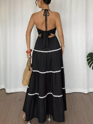 Black ruched halter maxi dress with tiered pleated skirt and white zigzag trim.