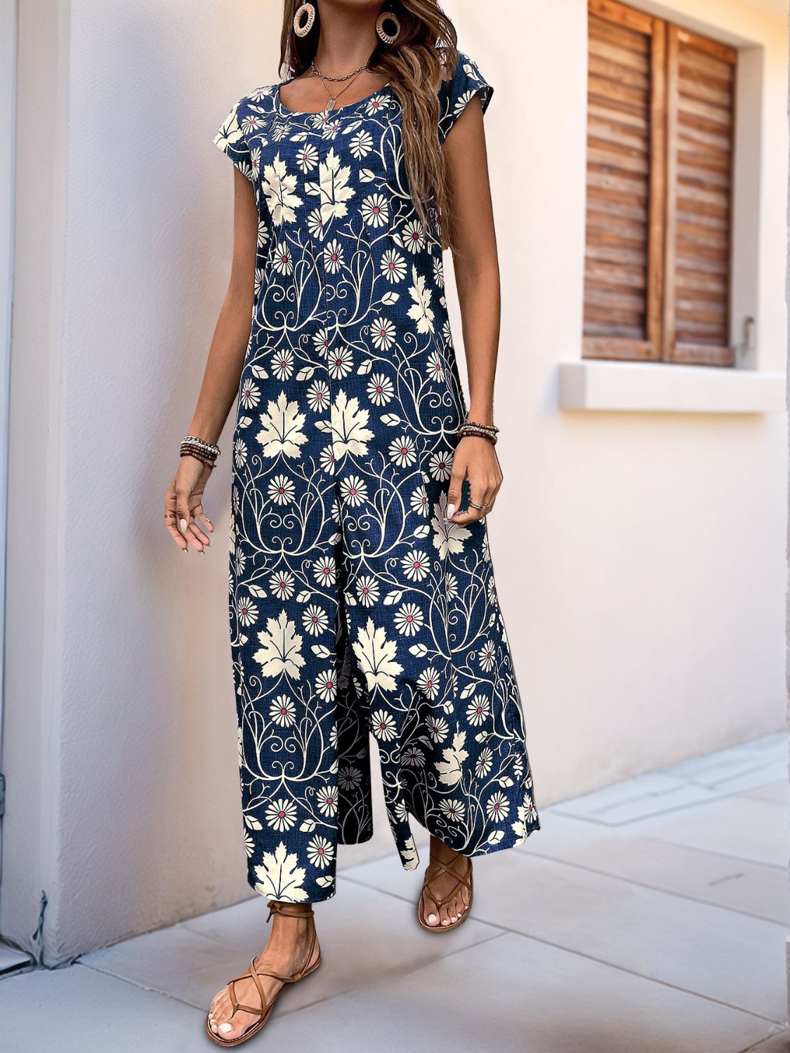 Botanical print culotte jumpsuit in dark green with short sleeves and a scoop neck.