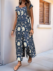 Botanical print culotte jumpsuit in dark green with short sleeves and a scoop neck.