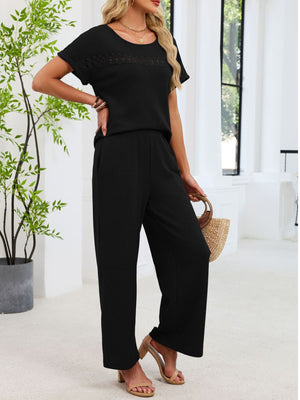 Black lace cutout knit two-piece set with wide-leg pants and short sleeves.