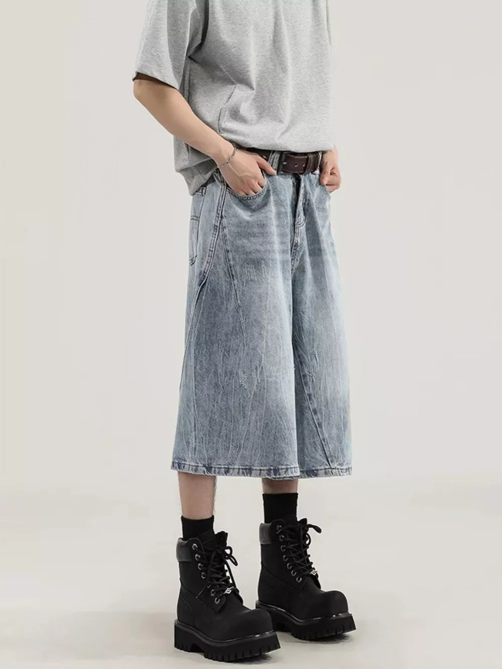 Light wash denim relaxed fit wide-leg capris with a distressed look, styled with a brown belt and black boots.