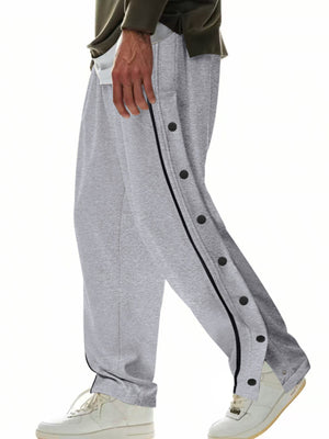 Grey track pants with full side snap buttons and black piping detail.