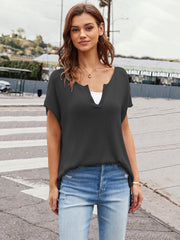 Black knit t-shirt with slit neckline and cap sleeves, styled with jeans.