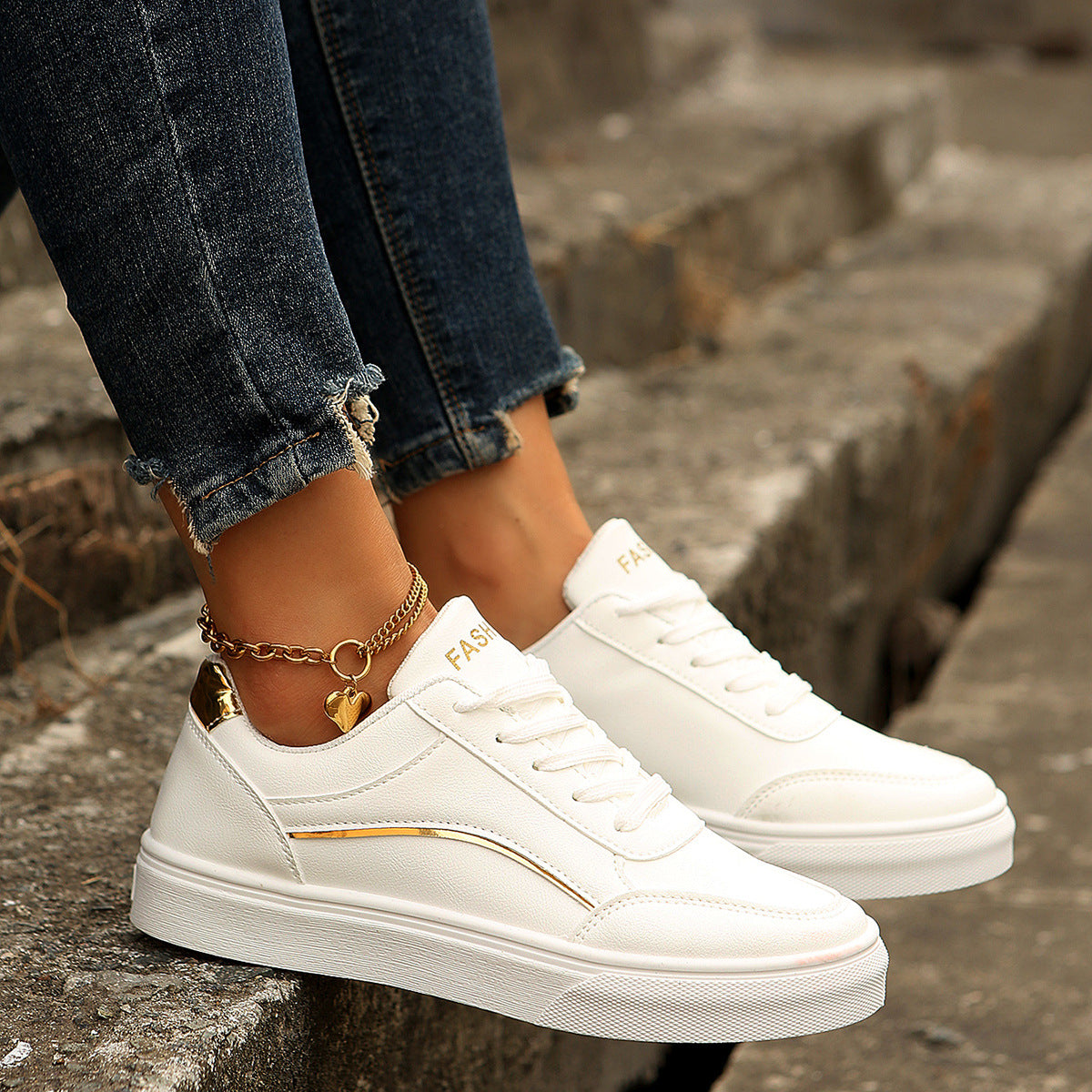 White lace-up casual sneakers with gold accents and a heart charm anklet.