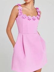 Pink mini dress with floral embellishments on the neckline and straps, featuring pockets.