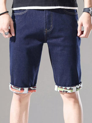 Men's dark blue denim shorts with rolled cuffs featuring a colorful geometric pattern.