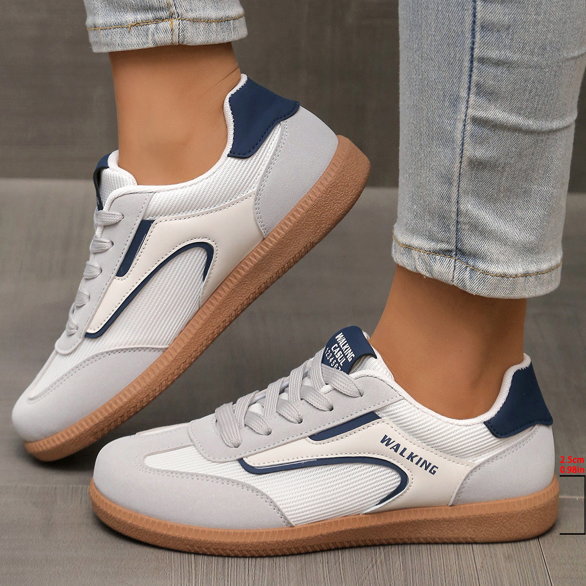 White and grey lace-up sneakers with blue accents and a brown sole.