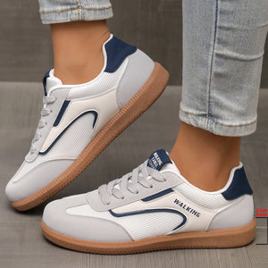 White and grey lace-up sneakers with blue accents and a brown sole.