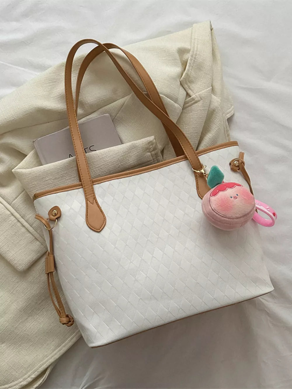 Textured diamond woven tote bag in white with tan straps and a plush charm.