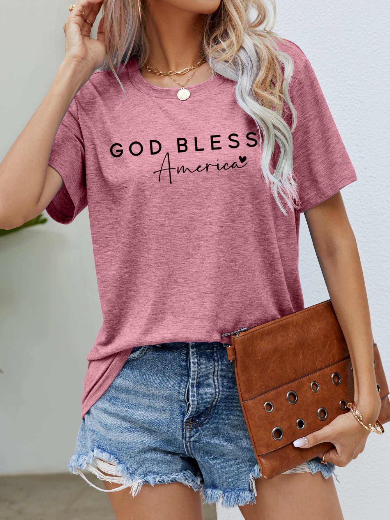 Dusty Pink God Bless America script graphic tee with crew neck and short sleeves.