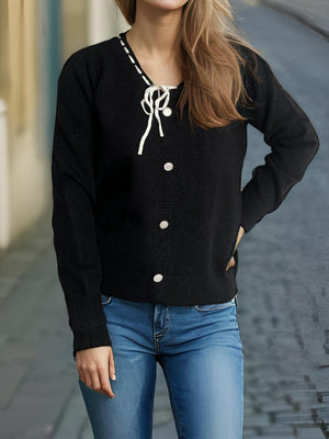 Black knit cardigan with white ribbon trim and buttons, v-neck, long sleeves.