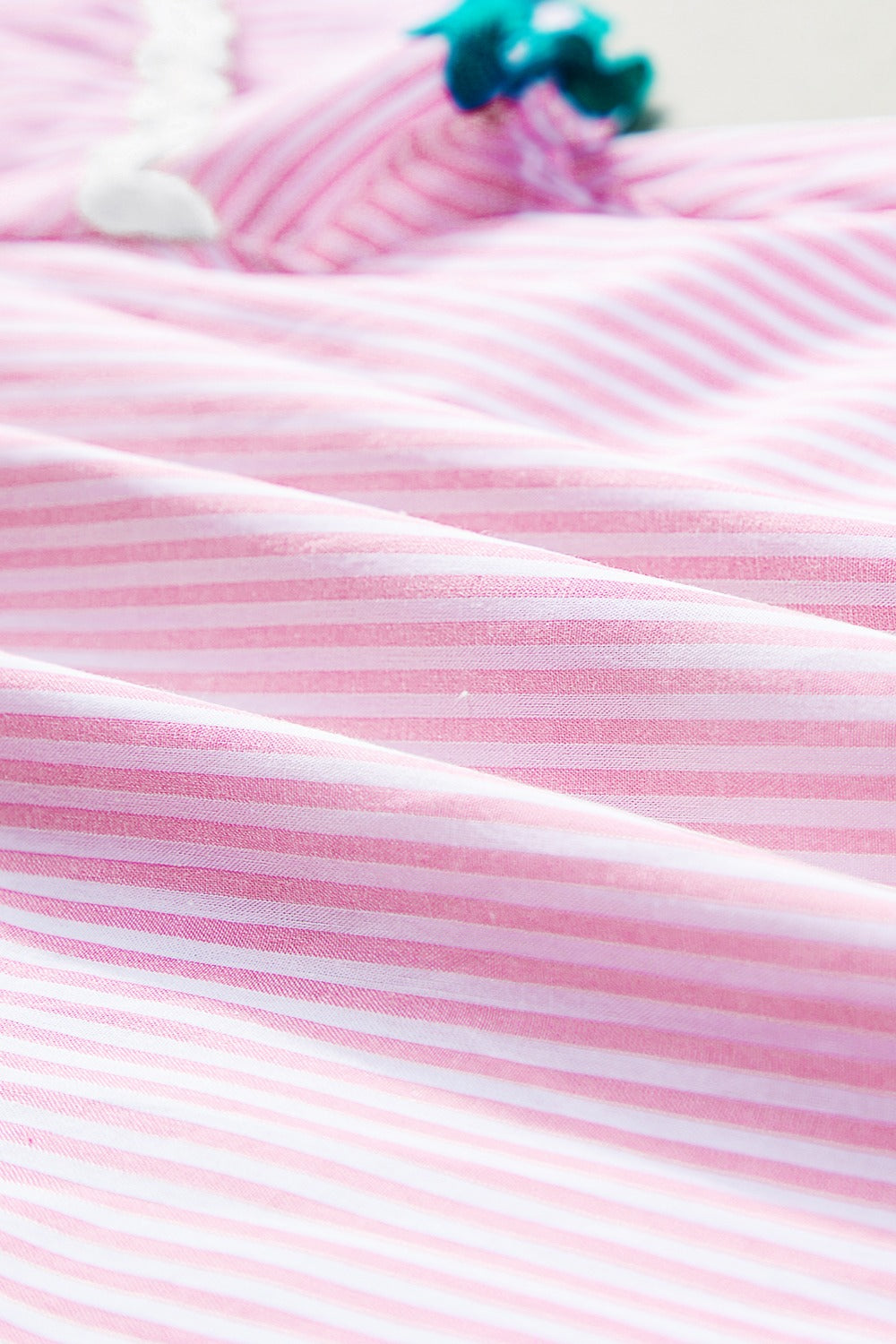 Blush pink and white striped blouse with scalloped trim detail.