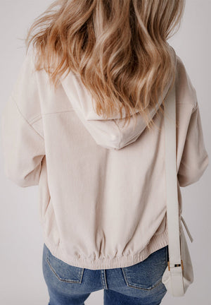 Cream corduroy bomber hoodie with drawstring hem and hood, relaxed fit.