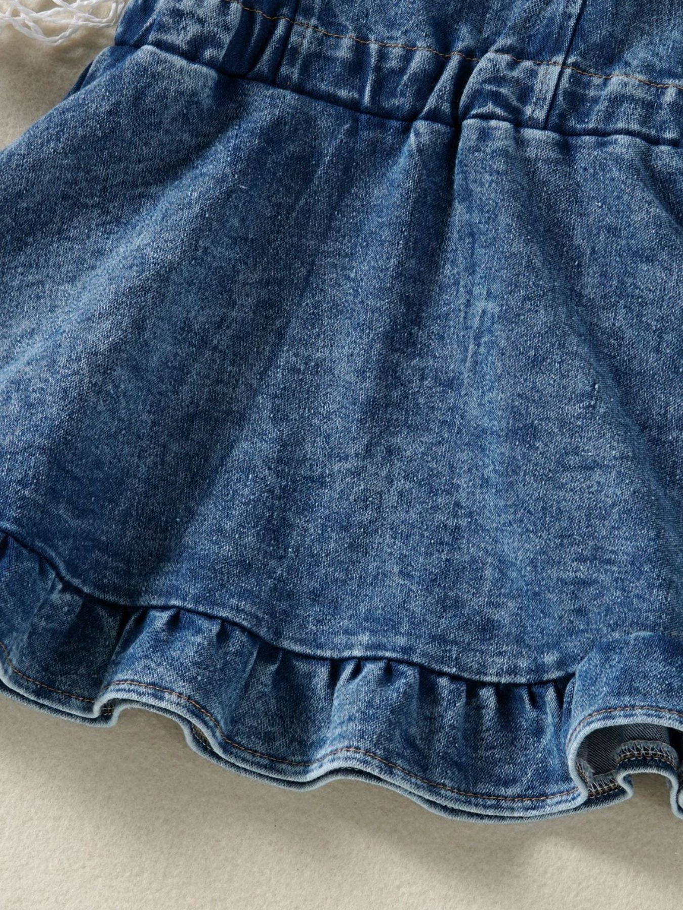 Adjustable denim overall dress for kids with ruffled hem and elastic waistband.