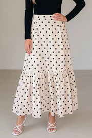 Beige polka dot maxi skirt with ruffled hem, styled with white strappy heels.