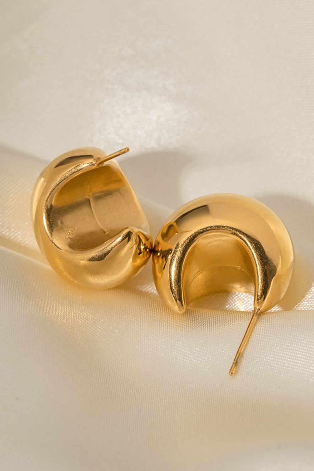 Gold sculptural crescent hoop earrings with a polished finish.