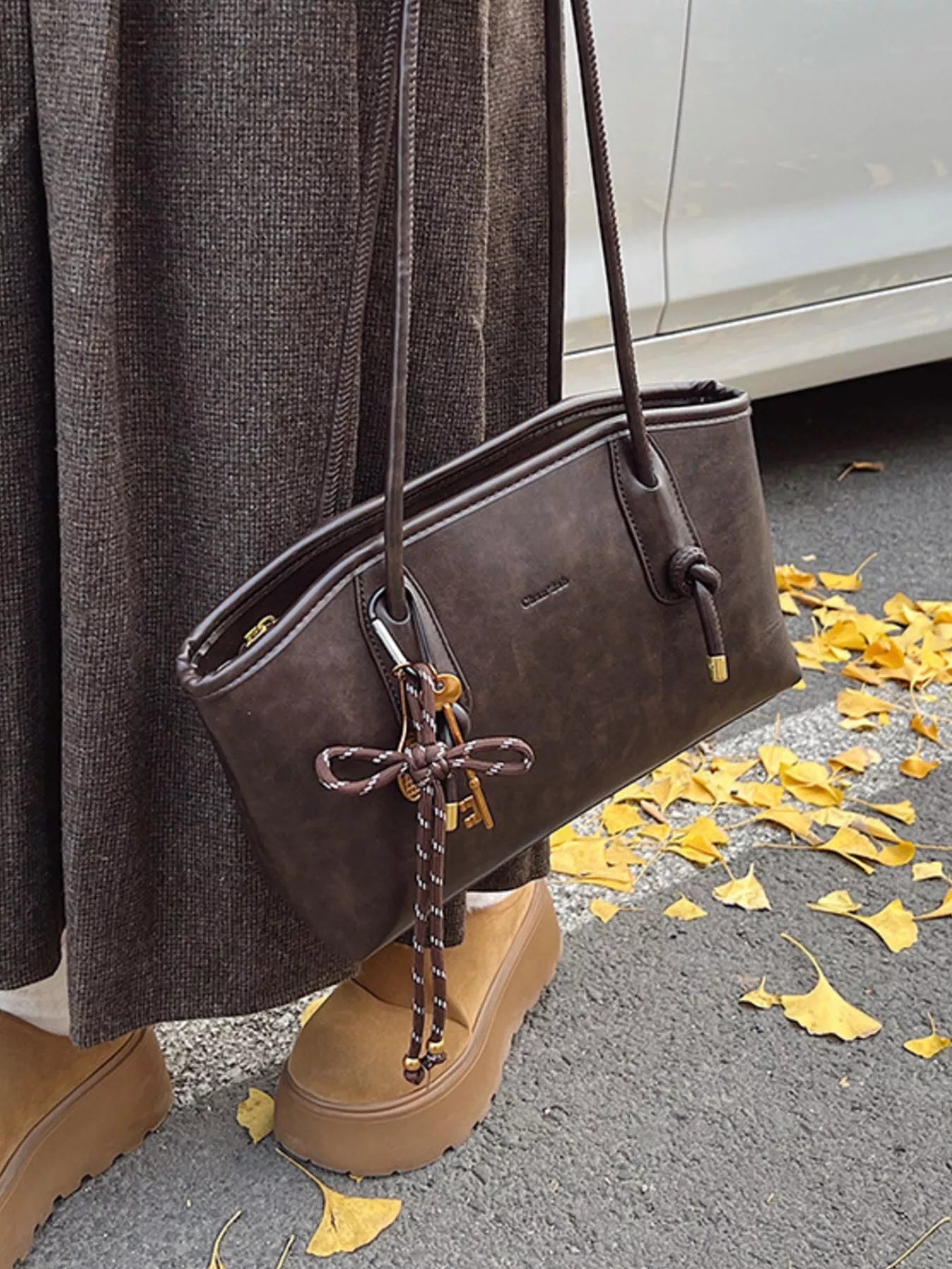Brown leather shoulder bag with key charm and rope detail.