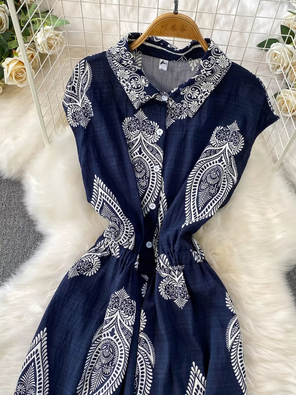 Navy blue buttoned romper with white paisley print, collared, short sleeves, elastic waist.