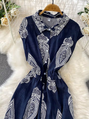 Navy blue buttoned romper with white paisley print, collared, short sleeves, elastic waist.