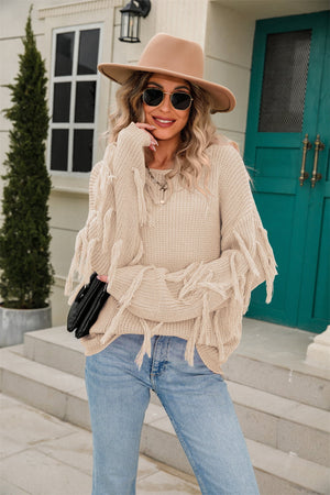 Sand fringe trim knit sweater with relaxed silhouette and casual styling.