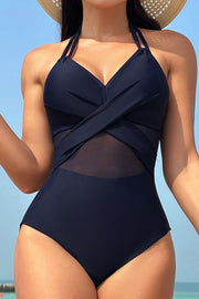 Dark blue one-piece swimsuit with crossover halter neckline and sheer mesh inset detail.