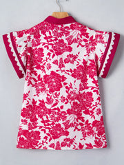 White polyester blouse with a bold pink floral print, lace trim on sleeves, and a stand collar.