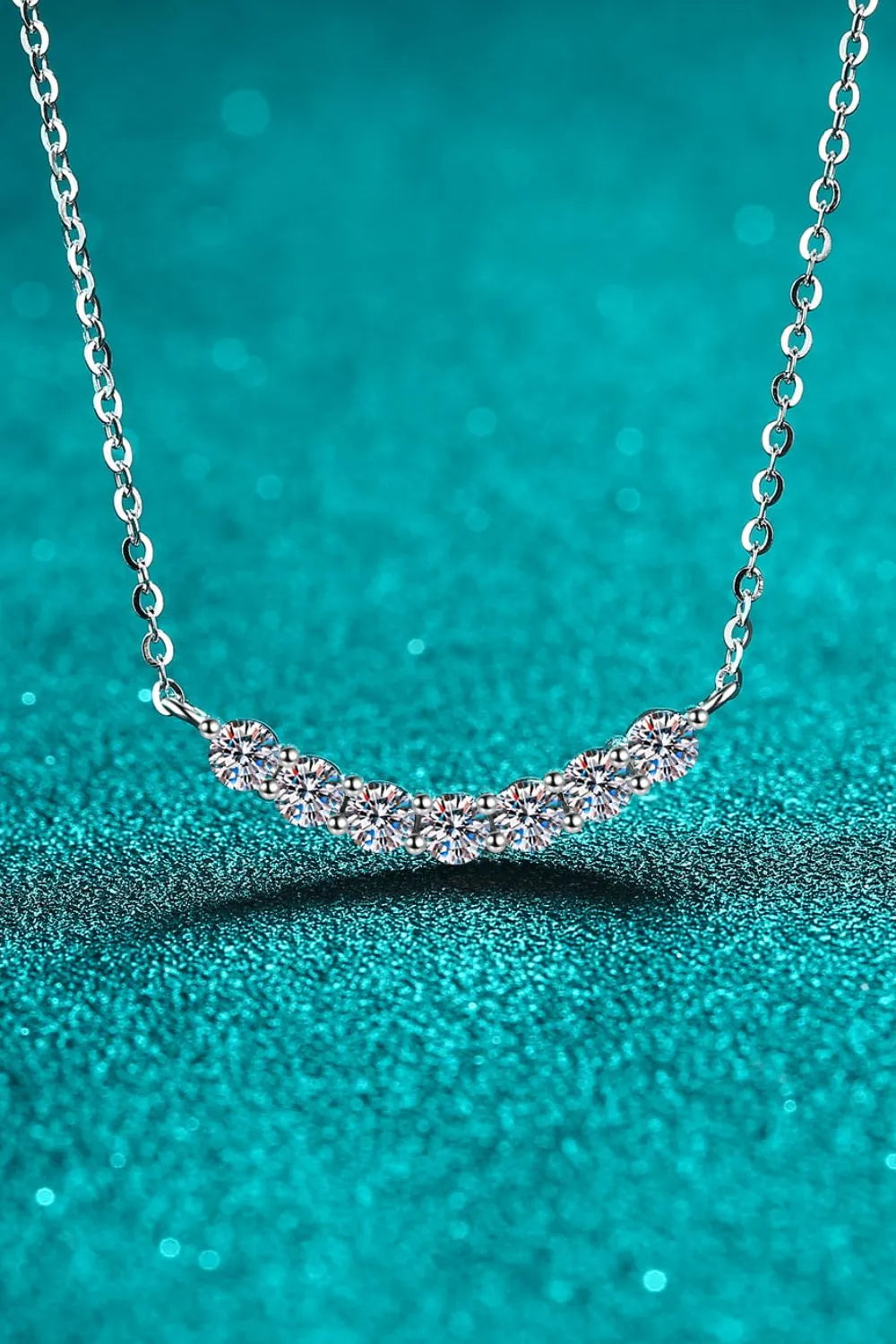 Silver moissanite necklace with a curved row of seven sparkling stones on a delicate chain.