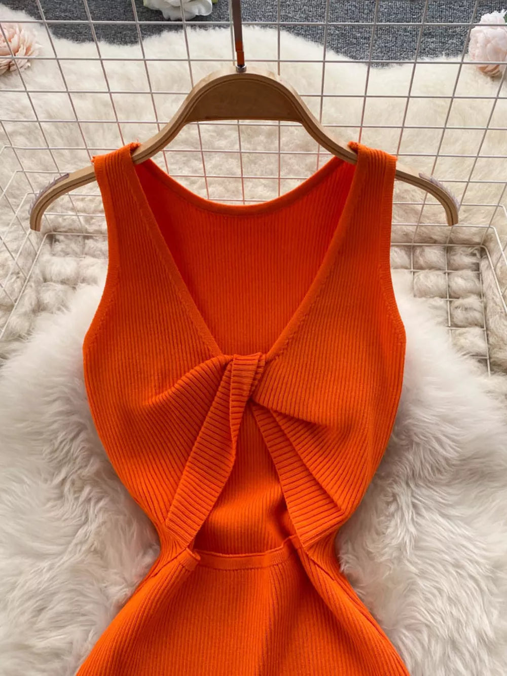 Orange ribbed knit midi dress with knot-back detail and cutout.
