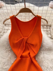 Orange ribbed knit midi dress with knot-back detail and cutout.