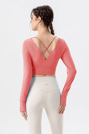 Coral long sleeve crop top with criss-cross back detail and thumbholes.