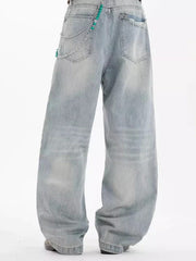 Washed cotton wide-leg men's jeans in light blue with distressed details and chain accessory.