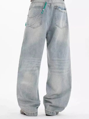 Washed cotton wide-leg men's jeans in light blue with distressed details and chain accessory.