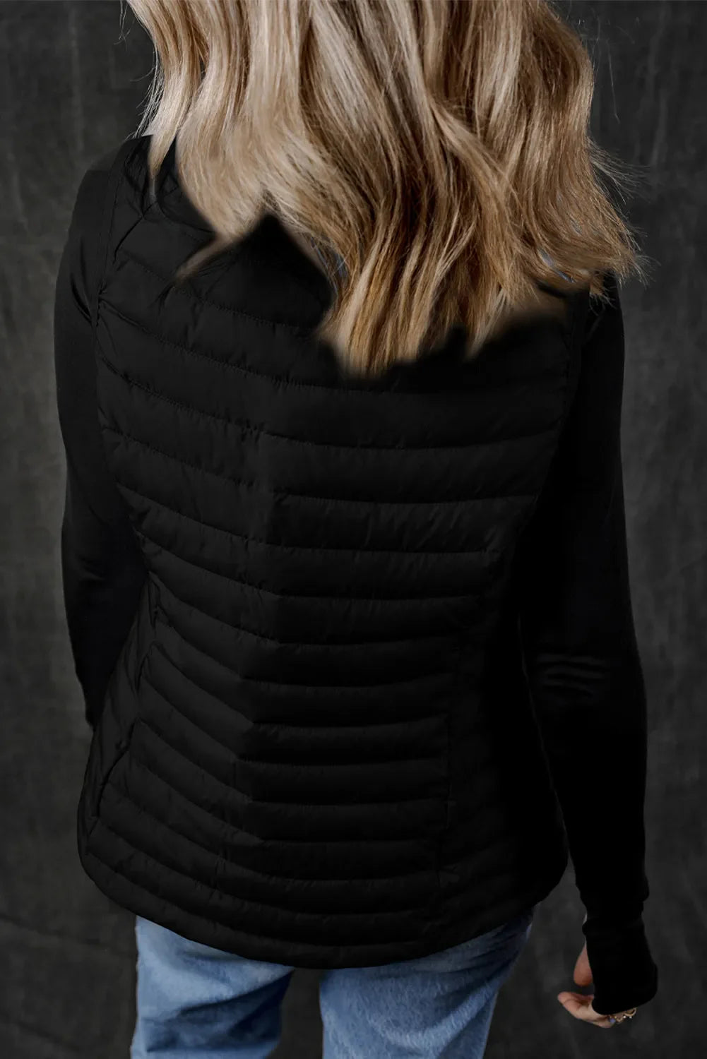 Black quilted puffer vest with horizontal quilting and long sleeves.