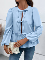 Light blue peplum blouse with keyhole neckline and bow details, long puff sleeves.
