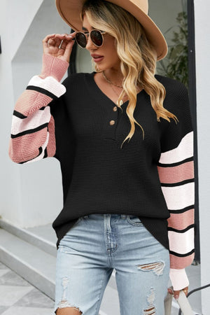 Black waffle knit henley sweater with pink and white striped sleeves and a v-neck.