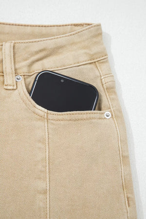 High-waisted cropped wide-leg jeans in tan denim with a phone in the pocket.