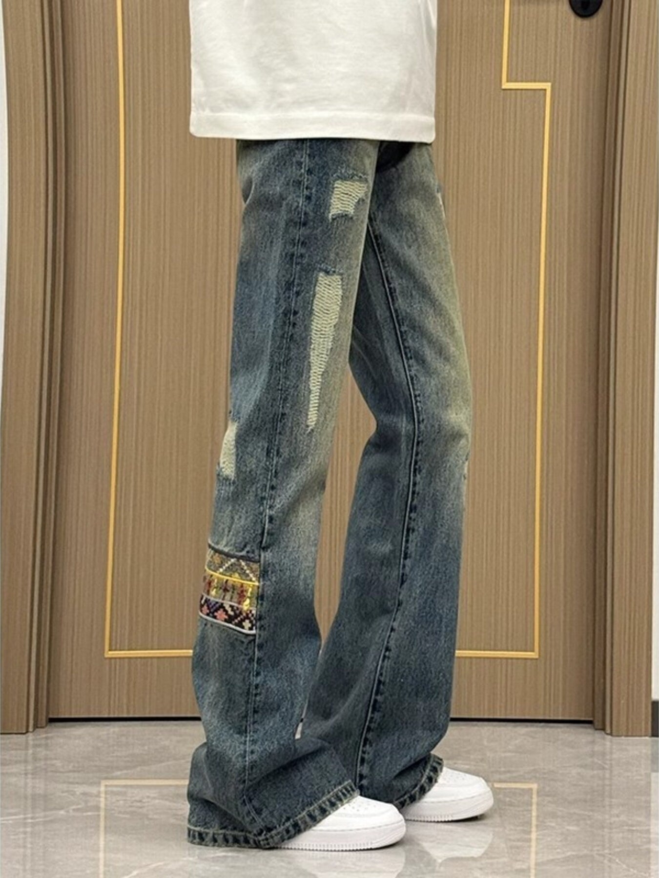 Distressed blue wash wide-leg jeans with patchwork detail and 100% cotton fabric.