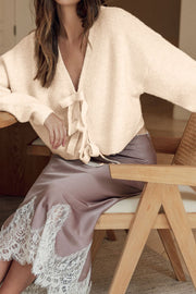 Ivory bouclé knit cardigan with tie-front detail and V-neck.