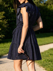 Navy polka dot dress with ruffle sleeves and tie waist, tiered skirt.