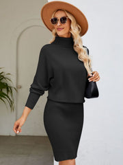 Black ribbed knit midi dress with dolman sleeves and turtleneck, styled with a hat and sunglasses.
