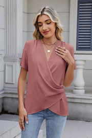 Dusty pink short sleeve blouse with draped crossover neckline and textured fabric